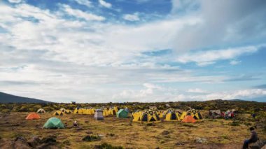 Kilimanjaro Dağı 'nın eteklerinde kamp kuran çadırlar. Çadırların üzerinde hareket eden bulutların güzel zaman çizelgesi. 
