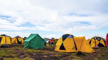 Kilimanjaro Dağı 'nın eteklerinde kamp kuran çadırlar. Çadırların üzerinde hareket eden bulutların güzel zaman çizelgesi. 