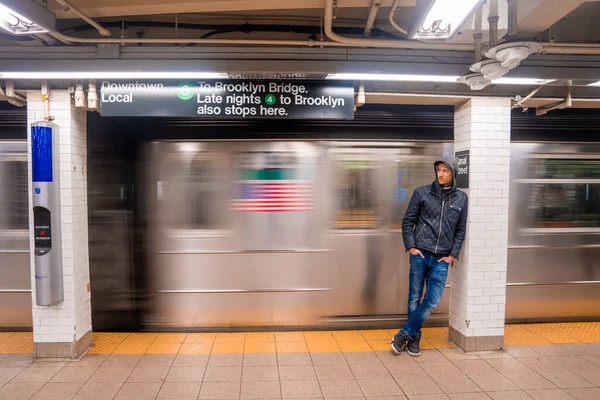 Subway train Canal street station platform with a man standing by the passing train. The NYC Subway is a rapid transit/transportation system in the City of NY.