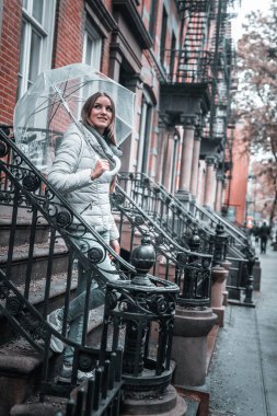 Genç bir kız elinde şemsiyeyle Greenwich Village 'ın eski bir New York semtinde merdivenlerden iniyor..