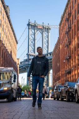 Washington caddesinde yürüyen genç adam, Brooklyn 'de arka planda bir Manhattan köprüsü ile.
