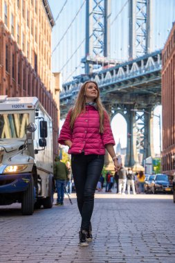 Washington caddesinde yürüyen genç ve güzel bir bayan, Brooklyn 'de arka planda bir Manhattan köprüsü ile.