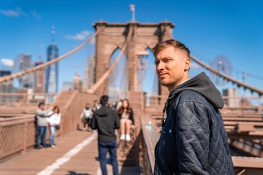 Brooklyn Köprüsü, New York, ABD - 21 Mayıs 2019. Manhattan manzaralı Brooklyn Köprüsü 'nde oturan genç adam..