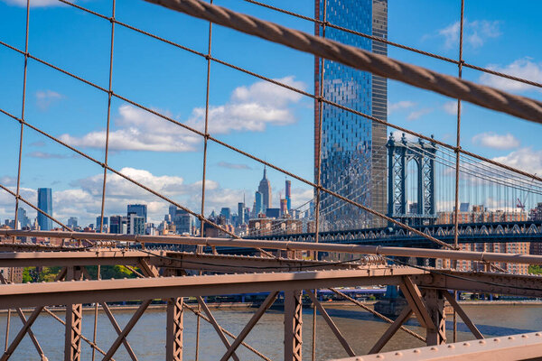 Close up view of the Brooklyn bridge with Empire State building in the background.