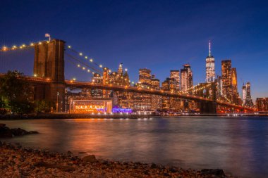 Brooklyn Köprüsü 'nün, Brooklyn Parkı' ndan Hudson Nehri 'nin diğer tarafındaki Manhattan manzaralı büyülü akşam günbatımı manzarası..