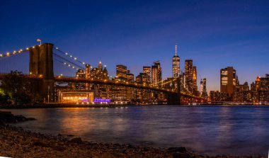 Brooklyn Köprüsü 'nün, Brooklyn Parkı' ndan Hudson Nehri 'nin diğer tarafındaki Manhattan manzaralı büyülü akşam günbatımı manzarası..