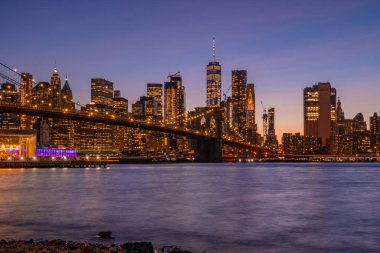 Brooklyn Parkı 'ndan Brooklyn Köprüsü' nün büyülü akşam mor gün batımı manzarası Hudson Nehri 'nin diğer tarafındaki Manhattan manzaralı..
