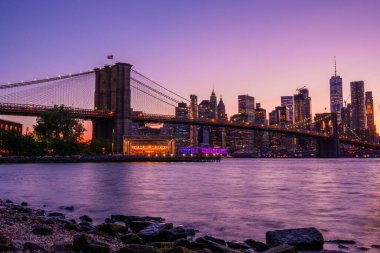 Brooklyn Parkı 'ndan Brooklyn Köprüsü' nün büyülü akşam mor gün batımı manzarası Hudson Nehri 'nin diğer tarafındaki Manhattan manzaralı..