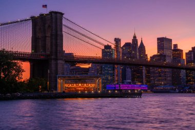 Brooklyn Parkı 'ndan Brooklyn Köprüsü' nün büyülü akşam mor gün batımı manzarası Hudson Nehri 'nin diğer tarafındaki Manhattan manzaralı..