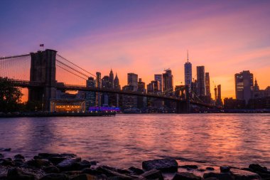 Brooklyn Parkı 'ndan Brooklyn Köprüsü' nün büyülü akşam mor gün batımı manzarası Hudson Nehri 'nin diğer tarafındaki Manhattan manzaralı..