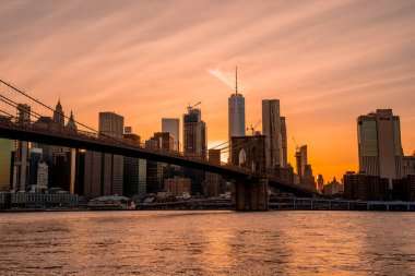 Brooklyn Köprüsü 'nün, Brooklyn Parkı' ndan Hudson Nehri 'nin diğer tarafındaki Manhattan manzaralı büyülü akşam günbatımı manzarası..