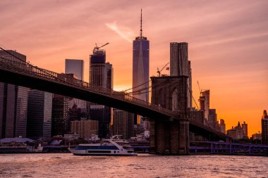 Brooklyn Köprüsü 'nün, Brooklyn Parkı' ndan Hudson Nehri 'nin diğer tarafındaki Manhattan manzaralı büyülü akşam günbatımı manzarası..