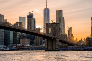 Brooklyn Köprüsü 'nün, Brooklyn Parkı' ndan Hudson Nehri 'nin diğer tarafındaki Manhattan manzaralı büyülü akşam günbatımı manzarası..