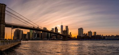 Brooklyn Köprüsü 'nün, Brooklyn Parkı' ndan Hudson Nehri 'nin diğer tarafındaki Manhattan manzaralı büyülü akşam günbatımı manzarası..