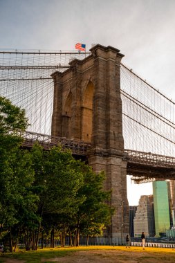 Brooklyn Köprüsü 'nün, Brooklyn Parkı' ndan Hudson Nehri 'nin diğer tarafındaki Manhattan manzaralı büyülü akşam günbatımı manzarası..