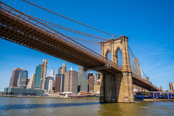 Brooklyn Bridge and the Lower Manhattan in New York City with clear blue sky.