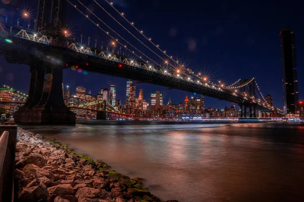 Beautiful panoramic view of the Manhattan Bridge in New York City at night with a Manhattan view across the Hudson river.