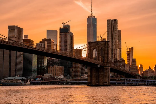 Brooklyn Köprüsü 'nün, Brooklyn Parkı' ndan Hudson Nehri 'nin diğer tarafındaki Manhattan manzaralı büyülü akşam günbatımı manzarası..
