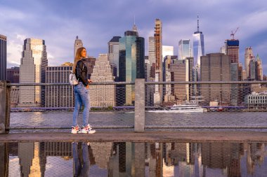 Brooklyn Parkı 'ndan Brooklyn Köprüsü' nün büyülü akşam mor gün batımının keyfini çıkaran seksi ızgara. Hudson Nehri 'nin diğer yakasında daha aşağı Manhattan manzaralı..