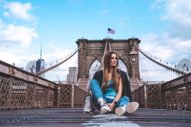 Genç seksi kız Manhattan manzaralı boş Brooklyn Köprüsünün keyfini çıkarıyor..