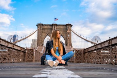 Genç seksi kız Manhattan manzaralı boş Brooklyn Köprüsünün keyfini çıkarıyor..