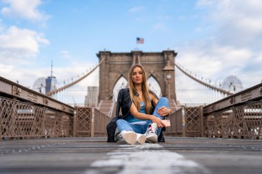Genç seksi kız Manhattan manzaralı boş Brooklyn Köprüsünün keyfini çıkarıyor..