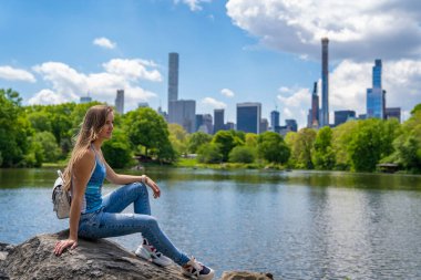 New York 'ta Central Park' ı keşfeden seksi bir kız. Güneşli bir günde, göletin kenarında. Etrafı gökdelenlerle çevrili.