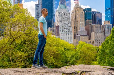 New York 'ta Central Park' ı keşfeden genç adam güneşli bir günde gökdelenlerle çevrili ana gölette.