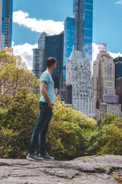 New York 'ta Central Park' ı keşfeden genç adam güneşli bir günde gökdelenlerle çevrili ana gölette.