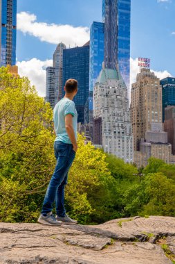 New York 'ta Central Park' ı keşfeden genç adam güneşli bir günde gökdelenlerle çevrili ana gölette.