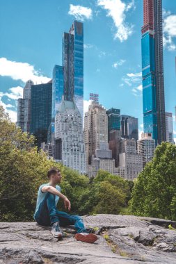 New York 'ta Central Park' ı keşfeden genç adam güneşli bir günde gökdelenlerle çevrili ana gölette.