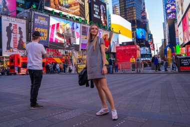 NEW YORK CITY - 9 Mayıs 2019: Times Square kalabalığını ve gece trafiğini keşfeden seksi kız. Site, yılda yaklaşık 40 milyon ziyaretçiyle dünyanın en çok ziyaret edilen turizm merkezi olarak kabul ediliyor..