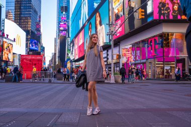 NEW YORK CITY - 9 Mayıs 2019: Times Square kalabalığını ve gece trafiğini keşfeden seksi kız. Site, yılda yaklaşık 40 milyon ziyaretçiyle dünyanın en çok ziyaret edilen turizm merkezi olarak kabul ediliyor..