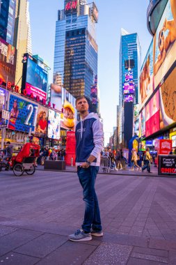 NEW YORK CITY - 9 Mayıs 2019: Times Meydanı 'ndaki kalabalığı ve trafiği araştıran genç adam. Site, yılda yaklaşık 40 milyon ziyaretçiyle dünyanın en çok ziyaret edilen turizm merkezi olarak kabul ediliyor..