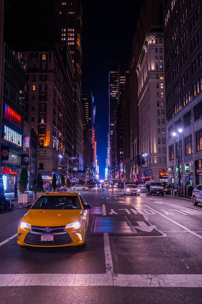 NEW YORK CITY - MAY 9, 2019: New York crowds and traffic at night. Empty road goes through Manhattan island near Time Square with taxi drivers.