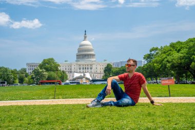 Washington, DC 'deki Kongre Binası' nın çimlerinde oturan genç adam..