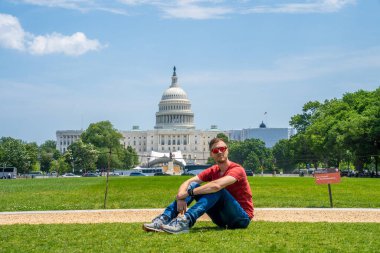 Washington, DC 'deki Kongre Binası' nın çimlerinde oturan genç adam..