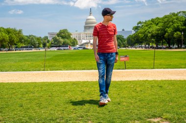 Washington, DC 'deki Kongre Binası' nın çimlerin üzerinde yürüyen genç adam..