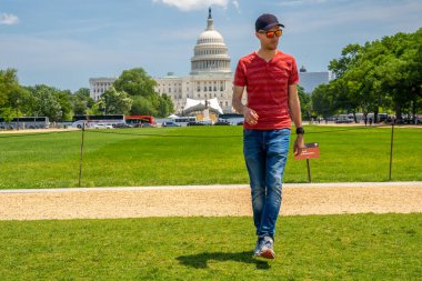 Washington, DC 'deki Kongre Binası' nın çimlerin üzerinde yürüyen genç adam..