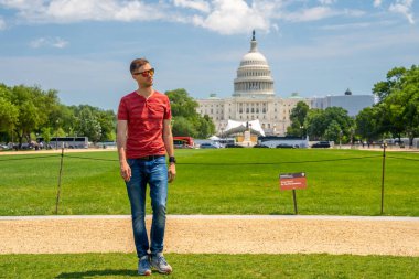Washington, DC 'deki Kongre Binası' nın çimlerin üzerinde yürüyen genç adam..