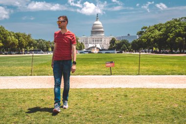 Washington, DC 'deki Kongre Binası' nın çimlerin üzerinde yürüyen genç adam..
