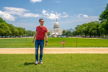 Washington, DC 'deki Kongre Binası' nın çimlerin üzerinde yürüyen genç adam..