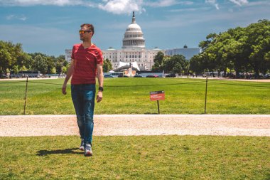 Washington, DC 'deki Kongre Binası' nın çimlerin üzerinde yürüyen genç adam..