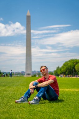 Güneşli bir günde Washington yakınlarında mavi gökyüzü arka planıyla Washington şehrini keşfeden genç adam..