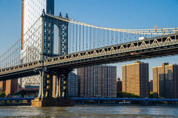 Close up view of the Manhattan bridge from the Brooklyn park with a lower Manhattan view on the other side of the Hudson river.