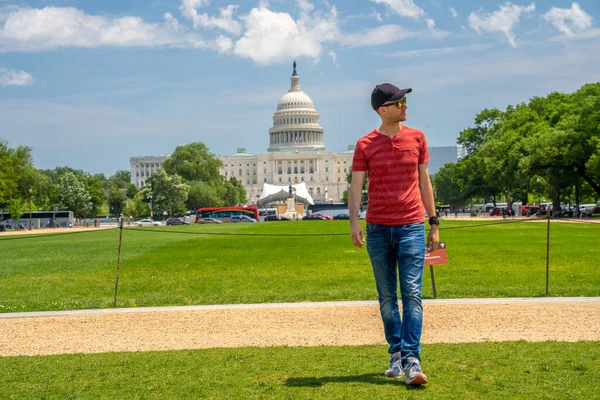 Washington, DC 'deki Kongre Binası' nın çimlerin üzerinde yürüyen genç adam..