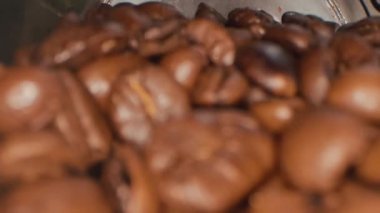 Kavrulmuş kahve çekirdekleri. Kavrulmuş kahve çekirdekleri yavaşça daireler çiziyor. Kavrulmuş kahve fasülyesi arka planı, üst manzara..