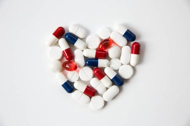 Heart pills, tablets, statins and drugs arranged into the shape of a heart on a white background with copy space clipart
