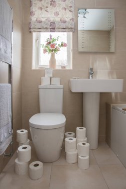 Beyaz süitli fayanslı bir banyo ve Coronavirus salgını sırasında panikledikten sonra tuvalet kağıtlarıyla kaplı.