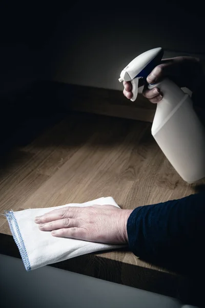 A close up of a pair of human hands cleaning the interior of a kitchen with Anti bacterial spray and a cloth to disinfect work surfaces during the Coronavirus outbreak and to kill germs and viruses with copy space